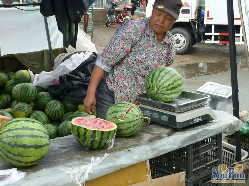 一个年青妇女想用二块钱买那个开裂了的西瓜,老板约了一下,按正常价要